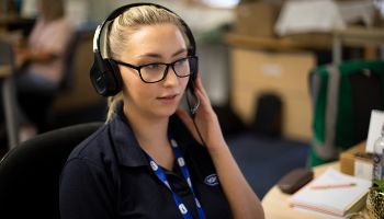 call centre worker in office wearing glasses and answering call