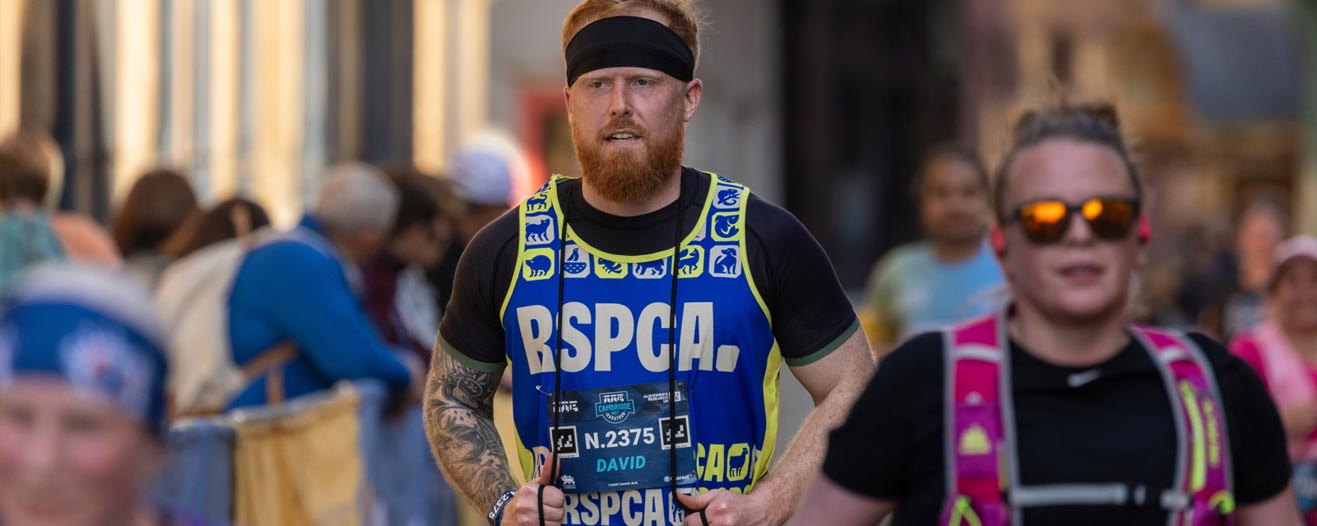 A male runner participating in a charity run event wearing an RSPCA running vest